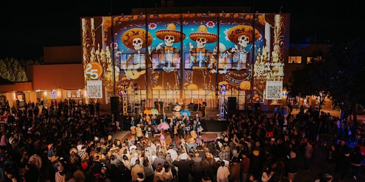 Photograph of event in a prior year, including dozens of attendees in front of a lit stage.