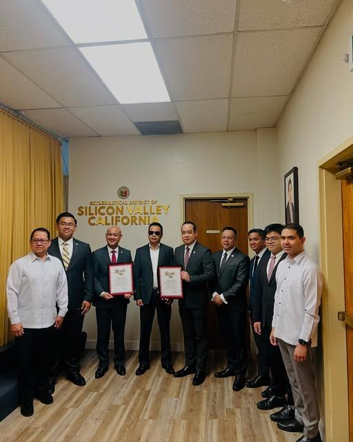 Staff member photographed with community members, holding up two certificates.
