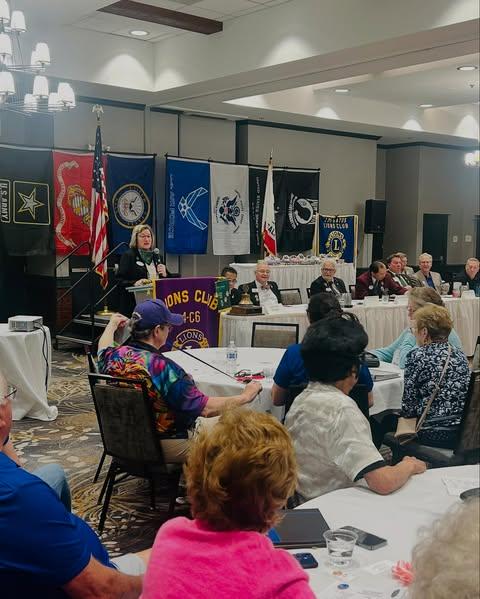 Lion’s club members and leaders, seated at a convention, watching a speech.