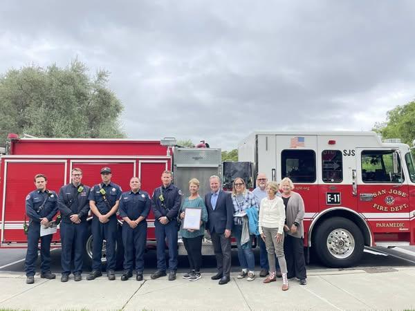 Senator Cortese in front of a red fire truck, surrounded by firefighters and community members.