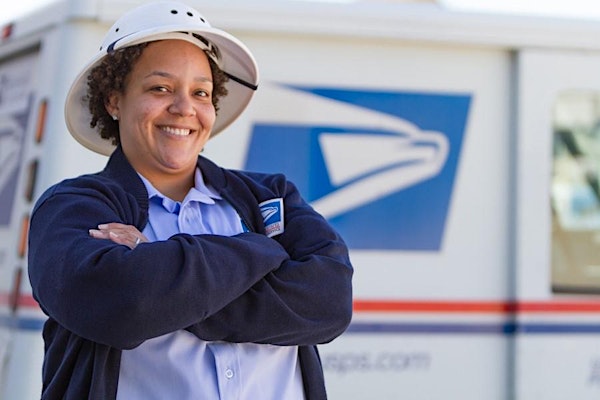 Image of postmaster in front of USPS delivery vehicle.