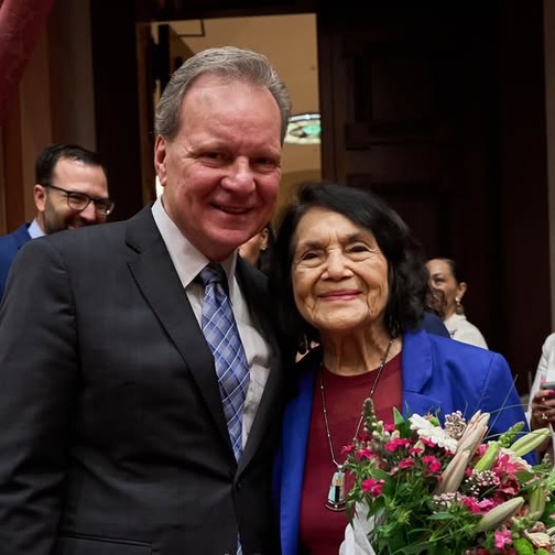 Senator Cortese standing alongside Dolores Huerta, both smiling for a photograph, Dolores Huerta holding flowers.