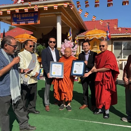 District Representative Phuong Nguyen at the Khemararam Buddhist Temple, surrounded by other officials and temple leadership, presenting a certificate of recognition.