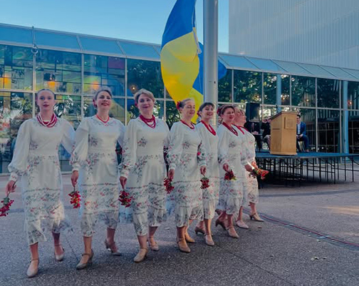 Members of the Open World delegation performing aside a Ukrainian flag.