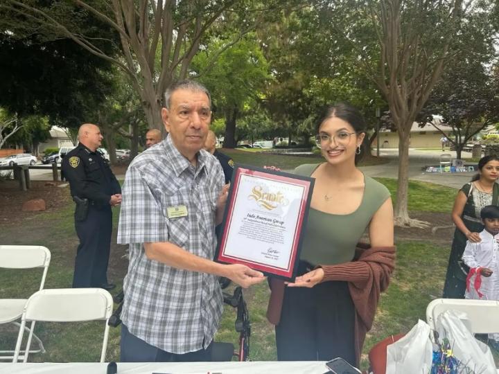 Staff member Meghan Bedi photographed presenting a certificate to Narendra Pathak