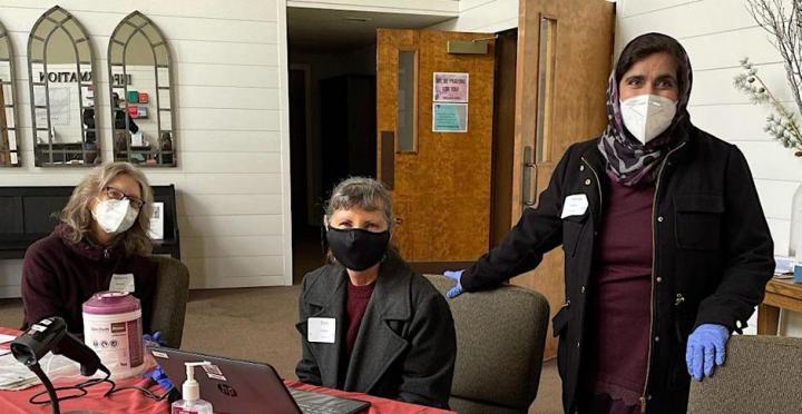 Image of three volunteers at a check-in table during a former Volunteer Blood Drive event