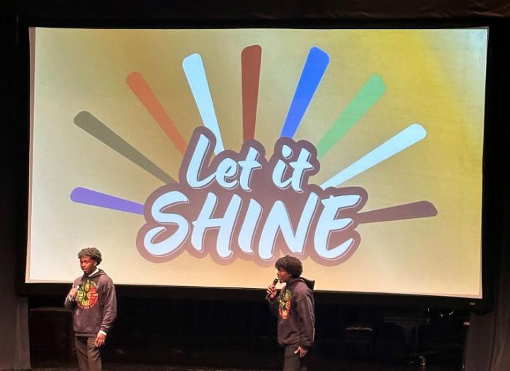 Students performing under a screen reading “Let it Shine”
