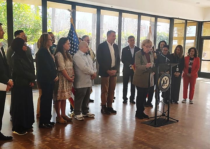 Congresswoman Zoe Lofgren speaking at a press conference among congressional and local leaders.