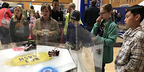 Photograph of young students around robotic constructions.